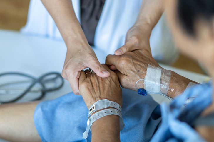 Elderly senior aged patient on bed with geriatric doctor holding hands for trust and nursing health care, medical treatment, caregiver and in-patient ward healthcare in hospital 