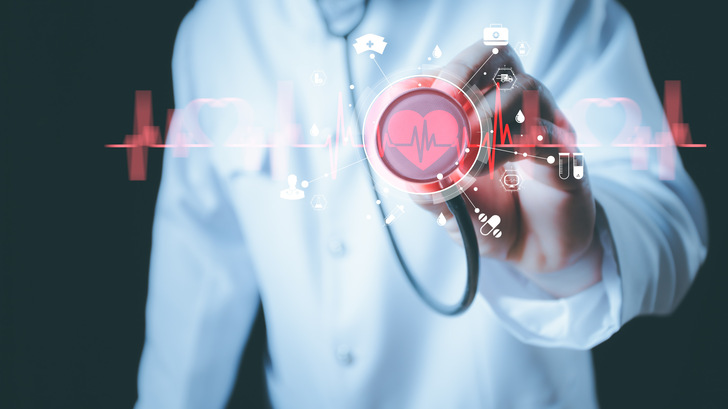 Ein Arzt hält ein Stethoskop an ein virtuelles Herzsymbol mit medizinischen Symbolen und einer EKG-Linie. - © wanniwat - stock.adobe.com