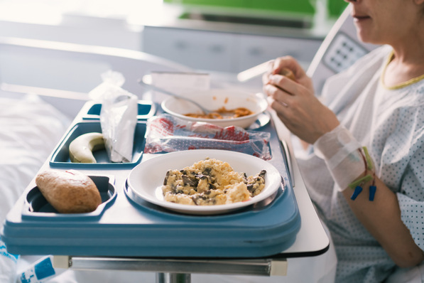 young woman who is hospitalized eating in the bed in the room the light meal that the nurses have brought her. health care and medical care in the hospital