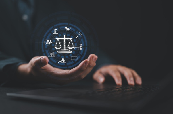 Alt-Text: „Ein medizinischer Gutachter tippt auf einem Laptop, während digitale Symbole einer Waage und juristische Icons die Verbindung zwischen medizinischer Begutachtung und Rechtsprechung visualisieren.“. - © Nirusmee - stock.adobe.com
