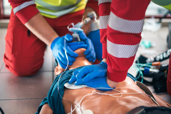 Zwei Sanitäter üben die Wiederbelebung und den Einsatz eines Defibrillators an einer medizinischen Übungspuppe. - © Chalabala - stock.adobe.com